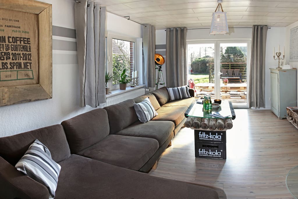 Die Wohnstube mit angeschlossener Küche hat eine große Couch, die für alle zusammen Platz bietet und einen Fernseher, sowie einem Kamin-Ofen. Durch die Tür kommt man über die Terrasse in den Garten.