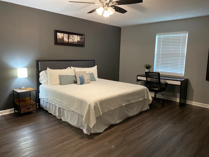 غرفة نوم رئيسية مع حمام داخلي وسرير بمقاس كبير ومكتب لمنطقة العمل. 