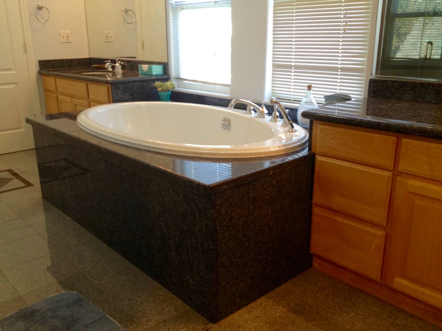 Spa bath with oversized bathtub and his and her sinks with large mirrors.
