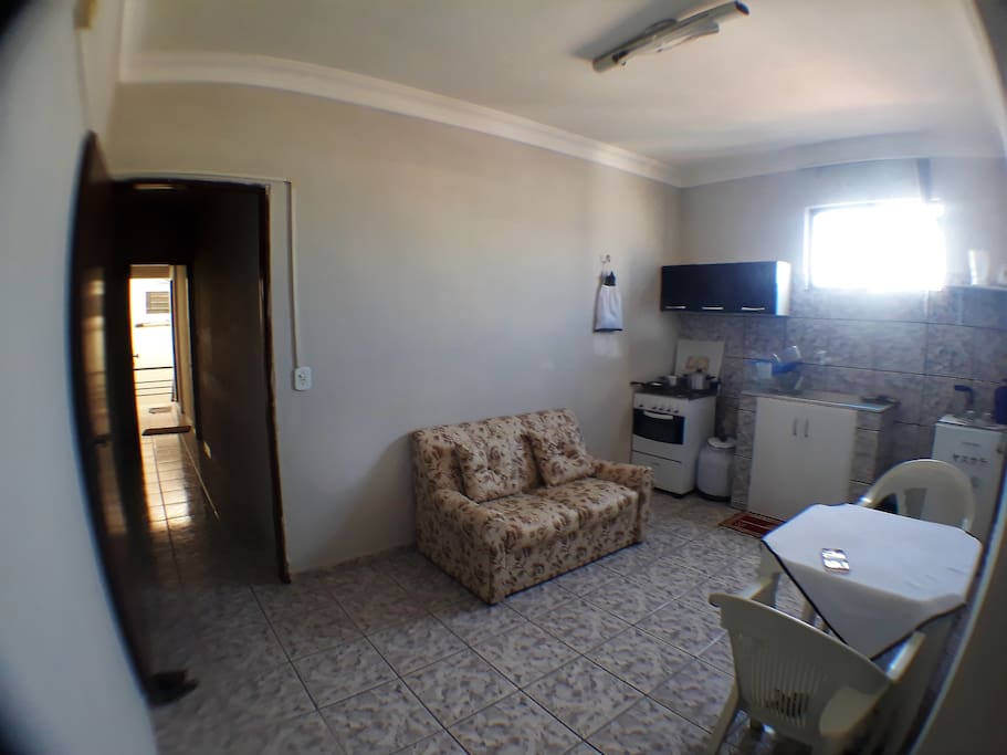 Sala conjugada com cozinha possui armador para rede