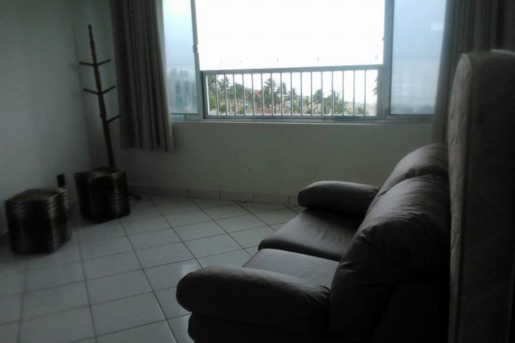 Quarto com sofá-cama de casal, tv a cabo, armário, colchões e ventilador de teto.