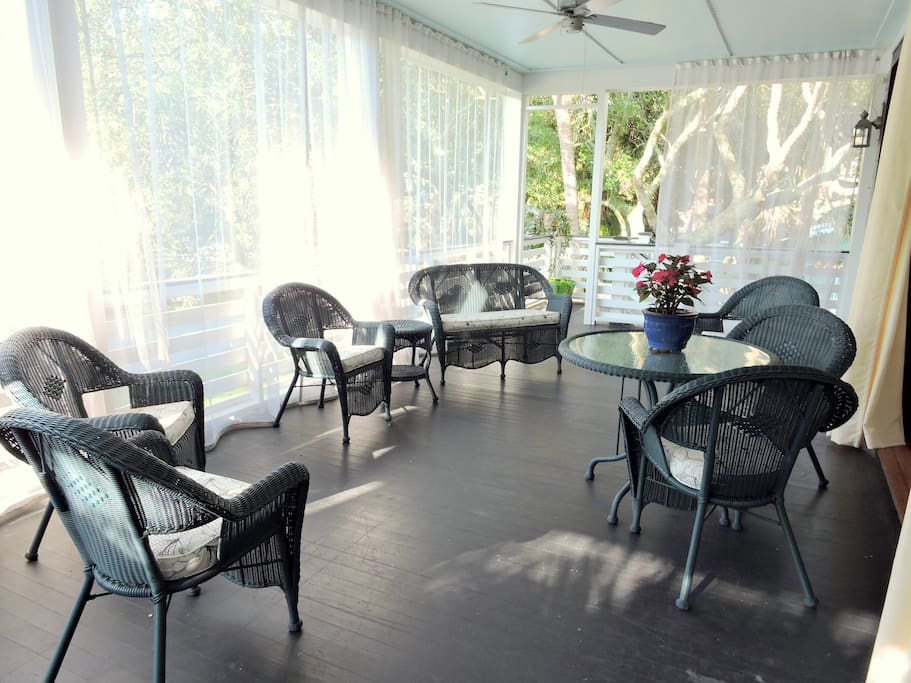 Beautiful outdoor porch with curtgains to curtail insects, and plenty of seating