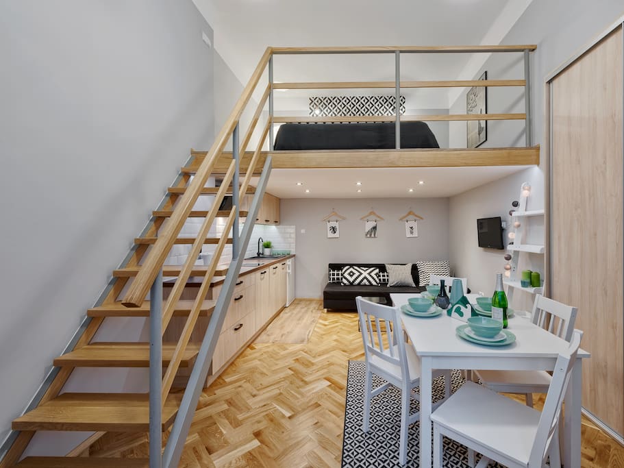 stairs to the mezzanine, bed, sofa, dining area
