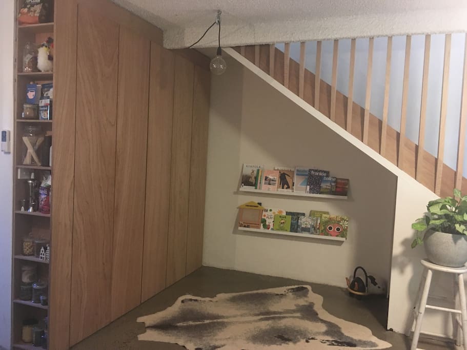 Kids play + reading nook with toys under the stairs