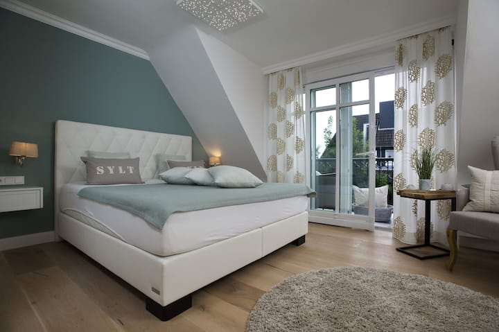 La chambre principale dispose d'un balcon et d'un grand lit à ressorts.