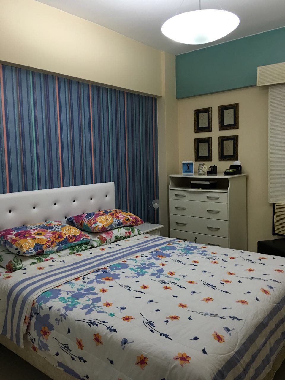 Habitación decorada con papel tapiz , pinturas y muebles con cajones, también tiene una puerta con zapatos