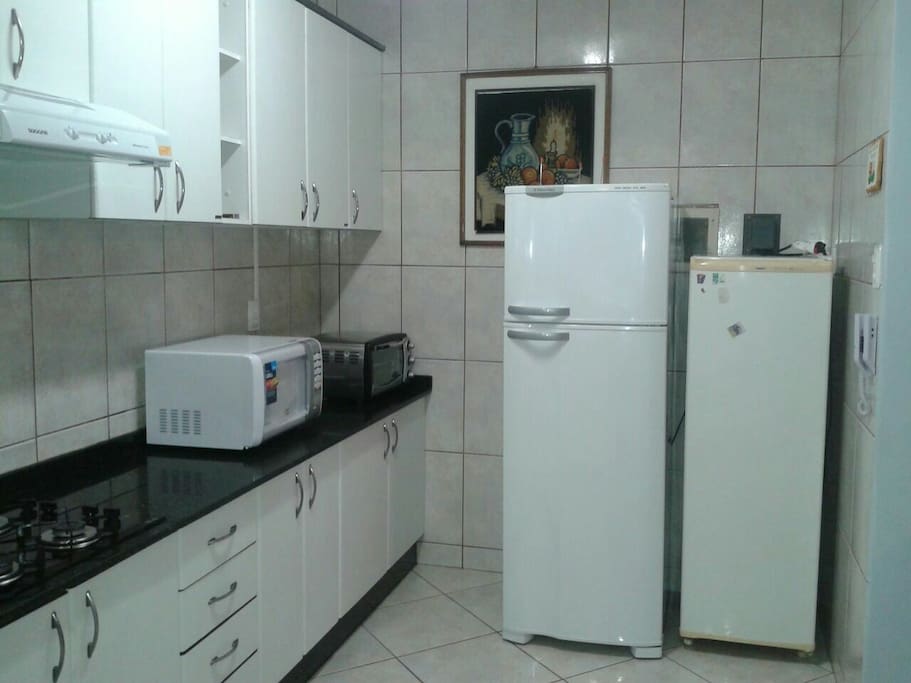 Cozinha com geladeira,freezer, micro-ondas e forninho elétrico.