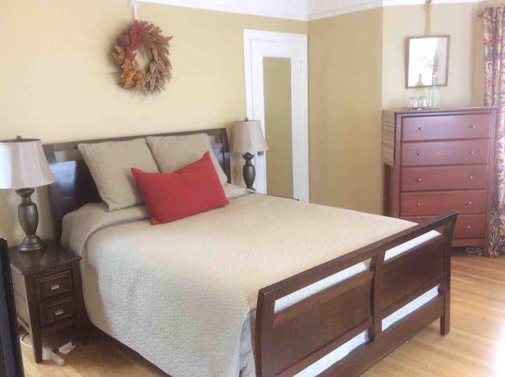 سرير بحجم كوين خارج القاعة مع باب فرنسي يؤدي إلى سطح الفناء الخلفي.