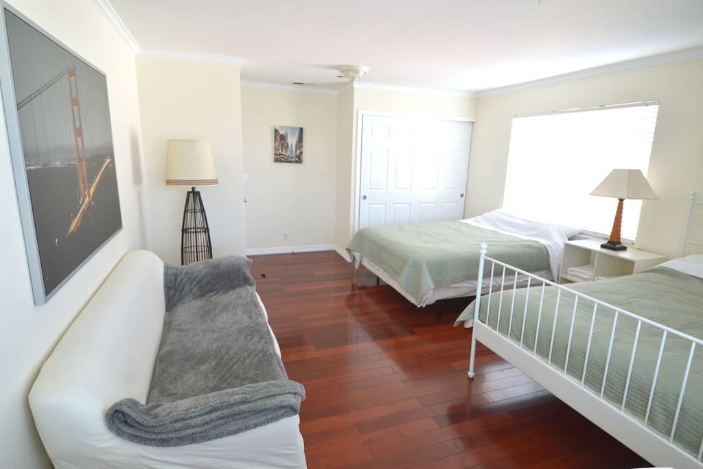 The bedroom with two queen beds, a work desk, and a large couch