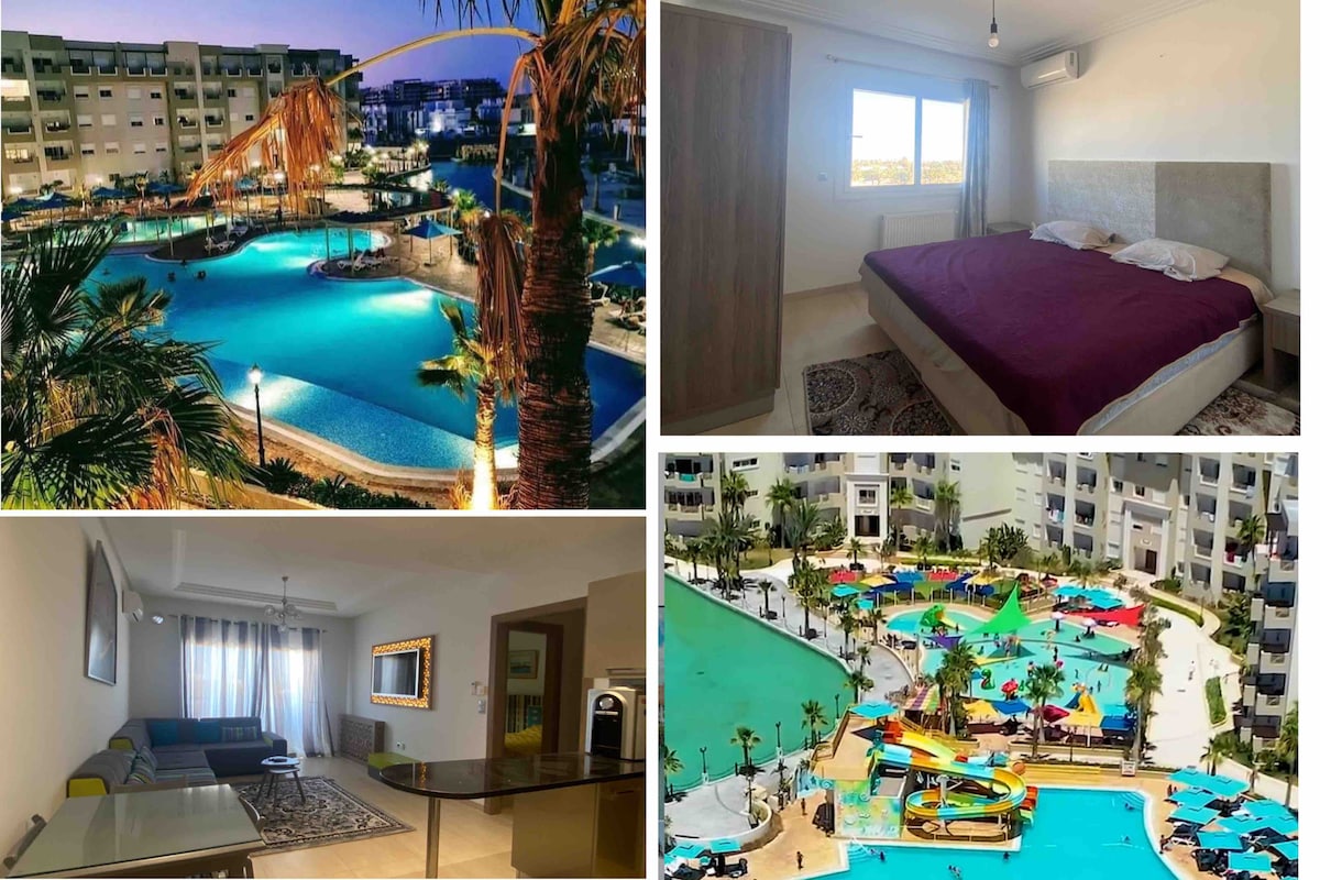 A spacious bedroom is fitted with a large bed and features light-colored walls. The bright interior is complemented by a window that allows natural light. Outdoor views showcase multiple pools surrounded by palm trees, while the vibrant colors of water slides and play areas enhance the resort’s family-friendly appeal.
