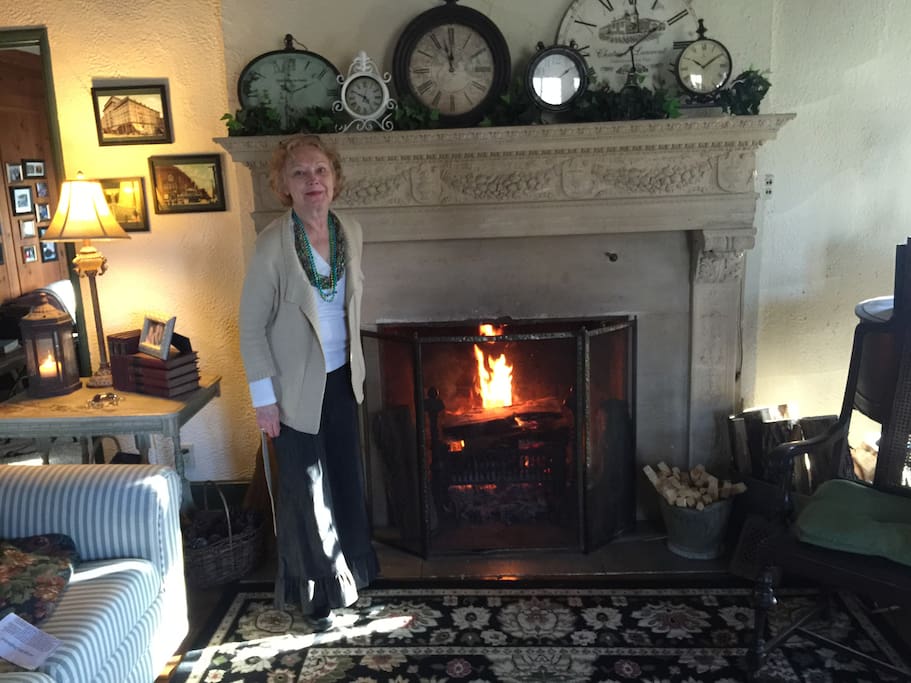 Host, Carol, in front of the living room fireplace