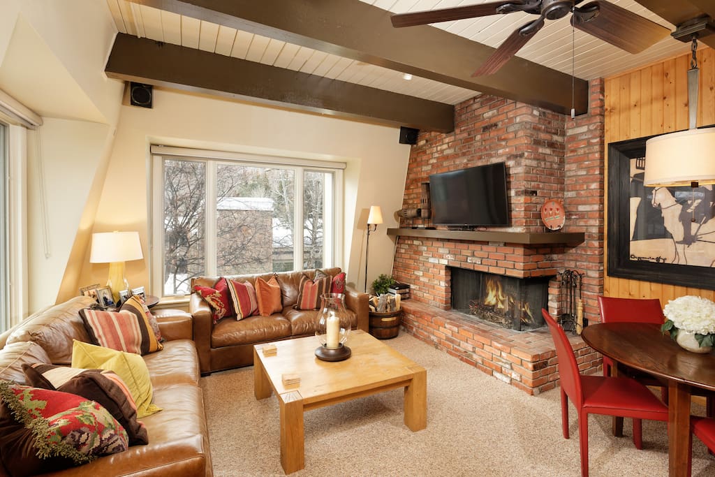 Cheerful living room with leather couches and a wood burning fireplace.