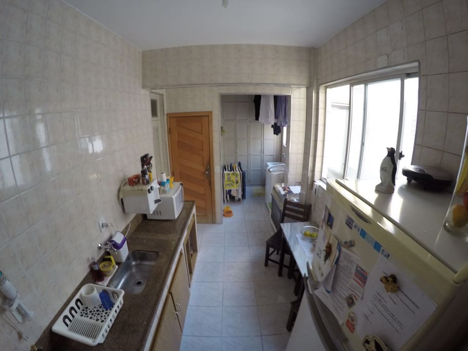 Ao fundo, área de serviço com máquina de lavar e tanque