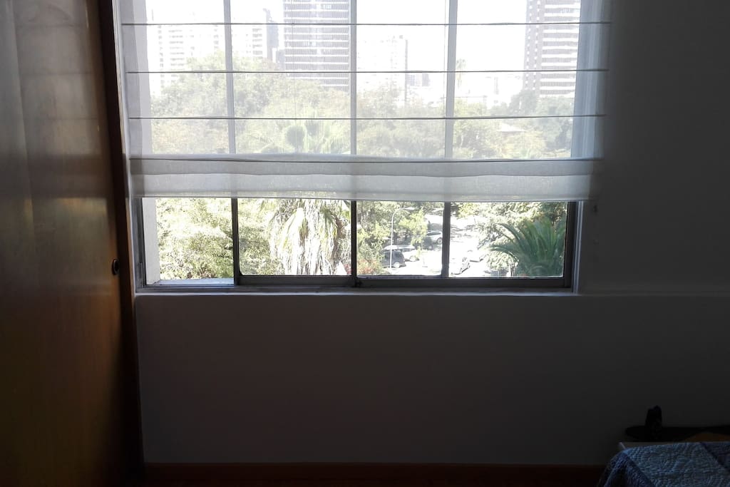 Habitación con ventana y vista al parque.