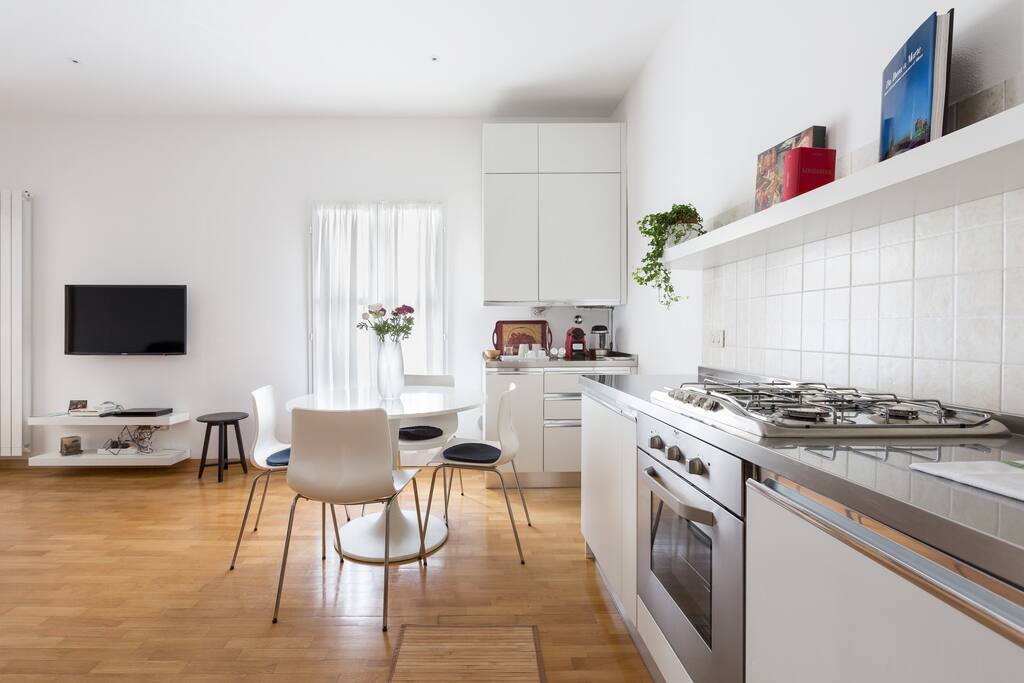 The living room: TV, AC, the dining table & the equipped kitchen