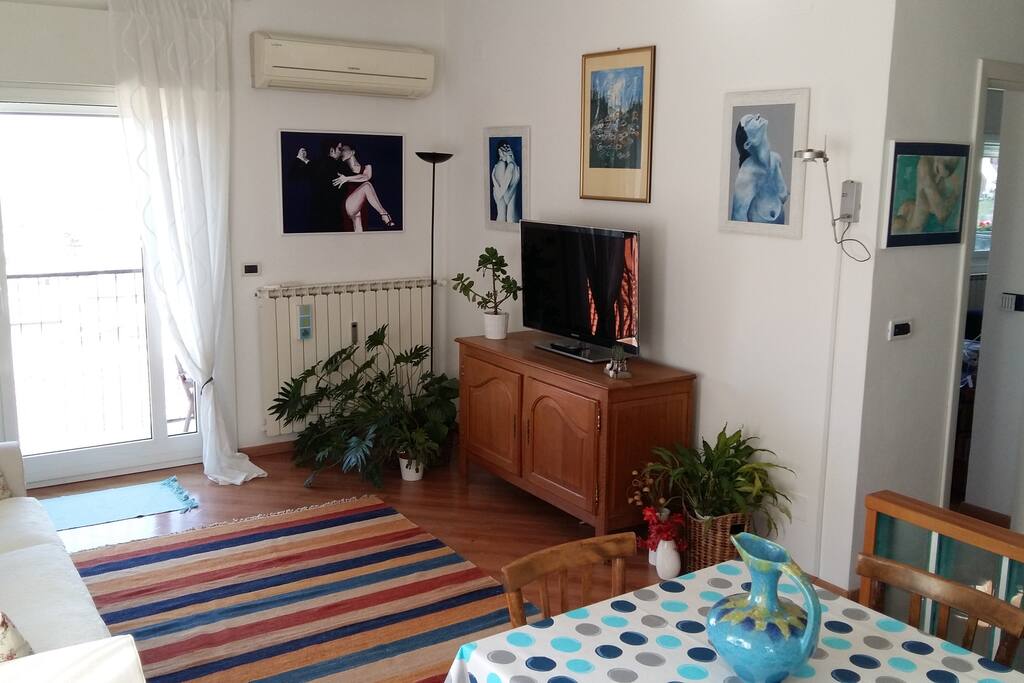Soggiorno, tavolo, TV e porta-finestra su terrazza