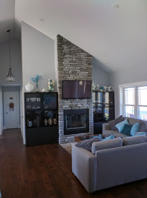 The family room is an open concept space with 15-foot high ceilings, mountain views, two sofas and comfy chairs overlooking the wood-burning fireplace (always stocked) and large-screen TV.
