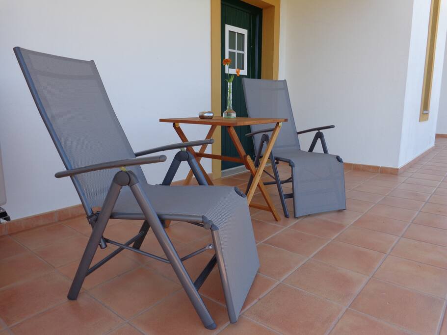 Privaat terras met terrasstoelen met zicht op de vallei en het zwembad.