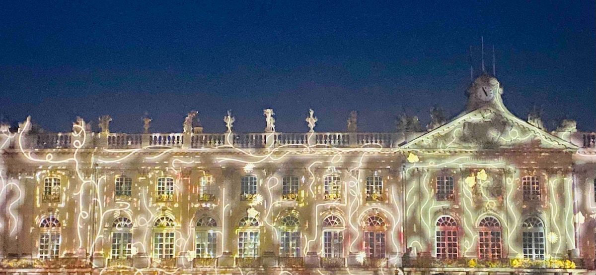 An illuminated historical building showcases intricate architectural details against a dark sky. Soft lighting highlights the façade, accentuating statuary and windows. The overall effect creates an enchanting scene, inviting guests to appreciate the building's grandeur and beauty.