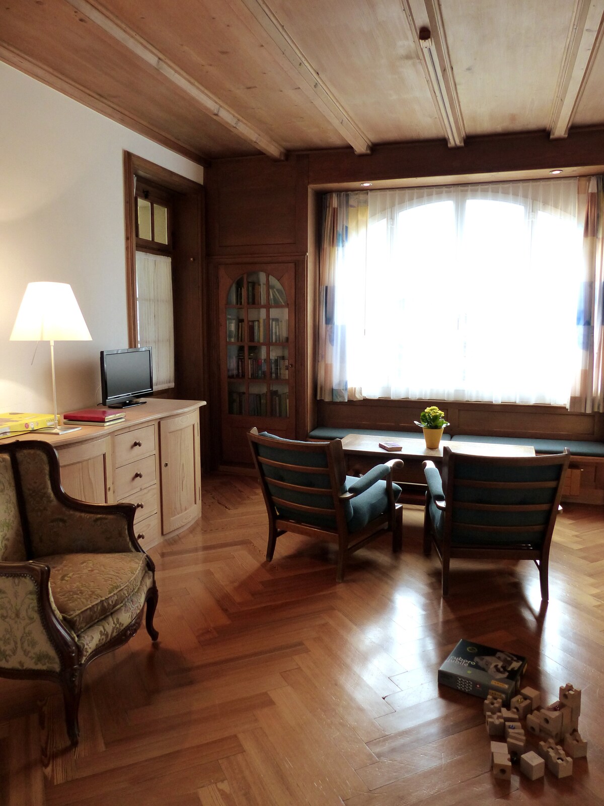 Sala de estar con biblioteca, sofá, TV y vistas a la montaña, así como cama adicional.