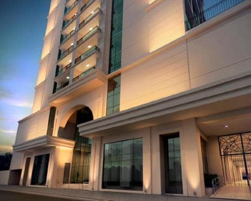 The modern building features a sleek facade with large glass windows and elegant architectural details. Soft lighting accentuates the structure, presenting a welcoming entrance beneath an expansive archway.
