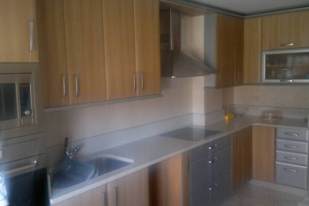 Cocina con electrodomésticos, nevera y utensilios básicos..