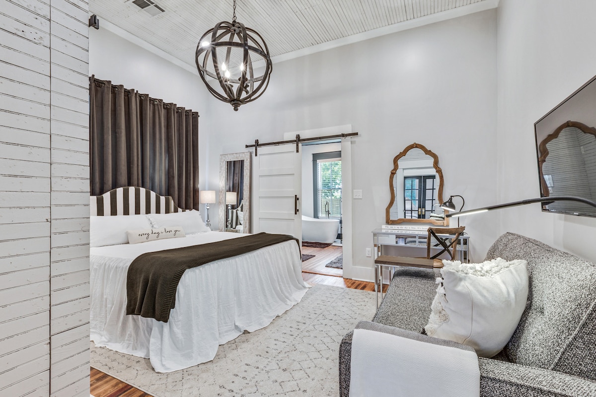 The tranquil primary suite with oh-so-cozy bedding, connected to a large bath with shower and soaking tub. A full-sized chaise, the perfect spot for a morning cup of coffee and reading. And handy for couch-crashing littles. 