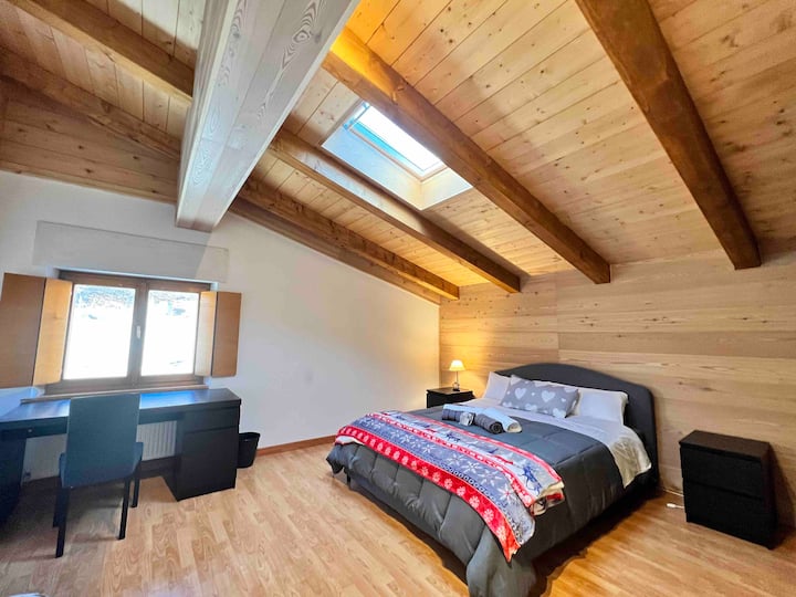 Chumba kikubwa na angavu kilicho na kitanda cha watu wawili na kitanda cha mtu mmoja, chenye dawati la kazi