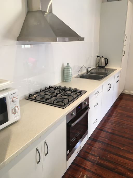 Kitchen with full amenities. Microwave, oven, gas stove, toaster, kettle and fridge.