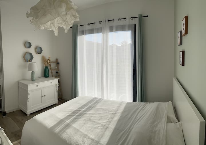Chambre numéro 2 avec un lit en 140 et rangements donnant sur une terrasse extérieur via une baie vitrée coulissante