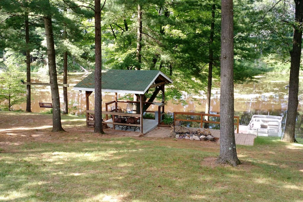 12'x12' pavilion and firepit near water's edge.