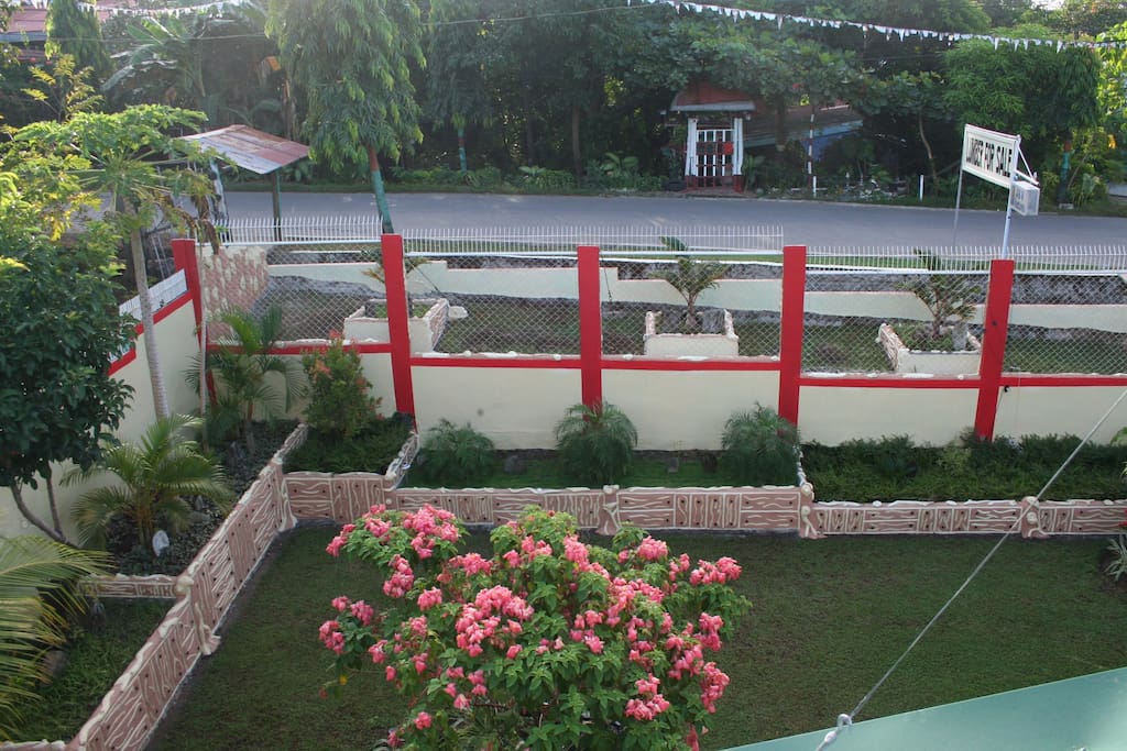 The view of the house from atop the roof. . The road on the background will lead to Provincial Capitol. It has native rustic design with plant boxes of different plant some art flowering . It has also has few fruit trees for shade.