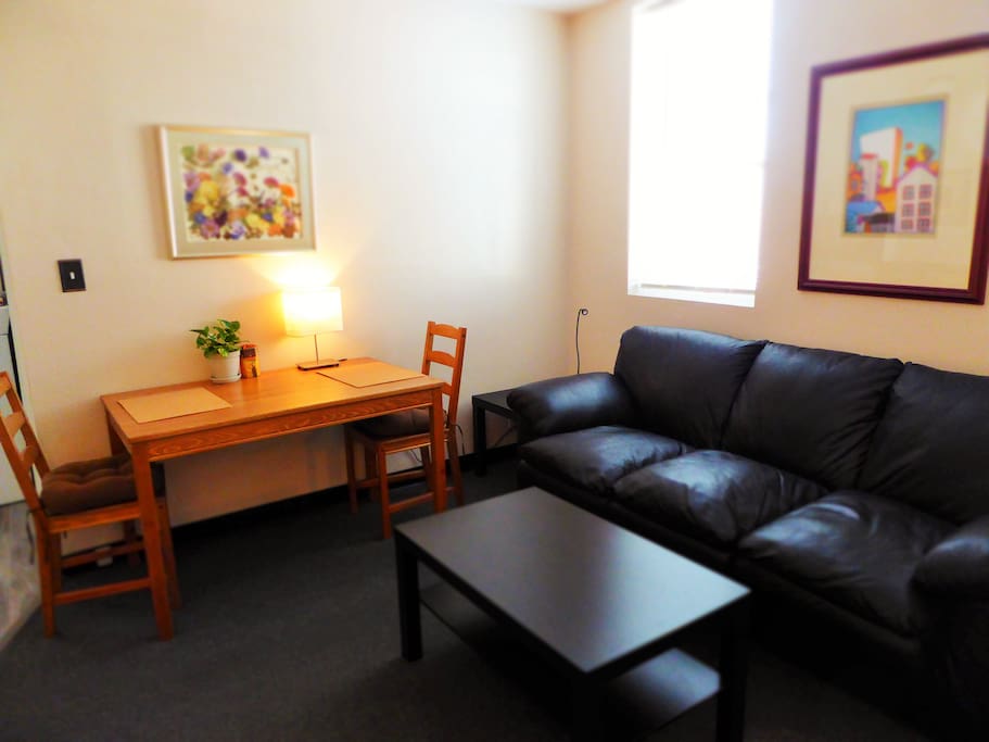 The living room features a comfortable sofa, original works of art, a digital TV and a beautiful dining table for two.