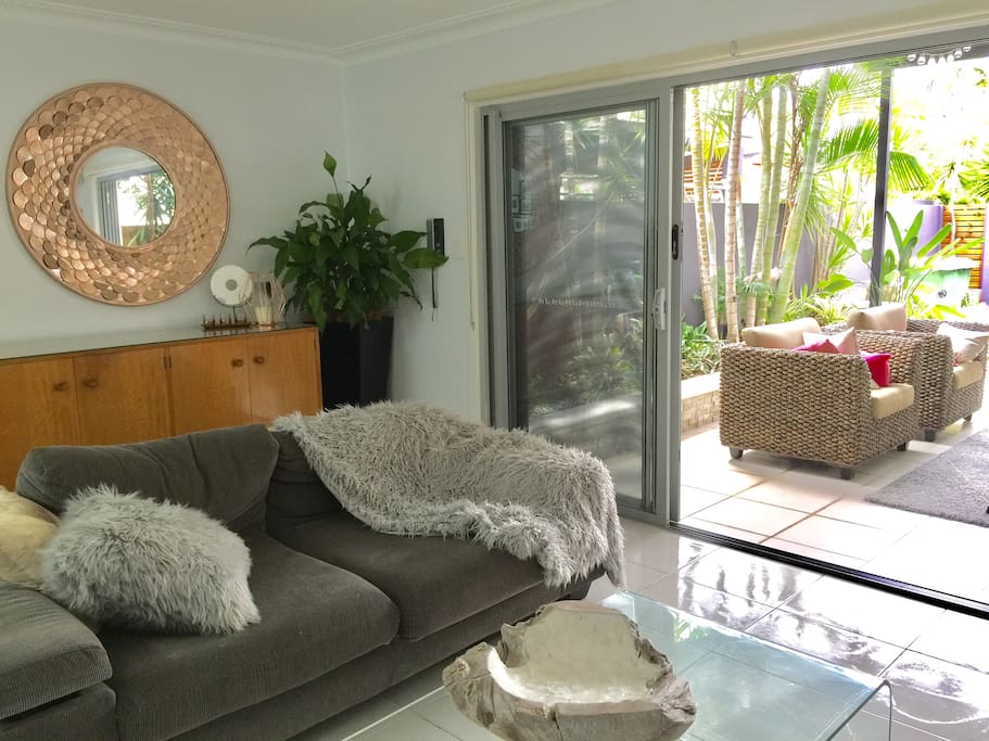 Open plan living room flowing out onto lovely tropical outdoor living.