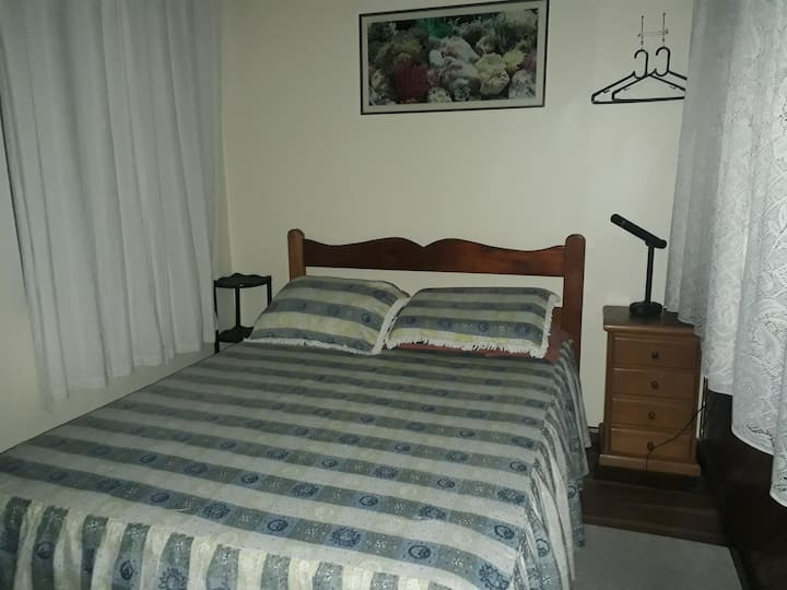 Spavaća soba 2, bračni krevet, višenamjenski ormarić, vješalice, stropni ventilator i stol.