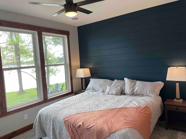 Main floor primary bedroom with King bed and shiplap accent wall overlooking the lake.
