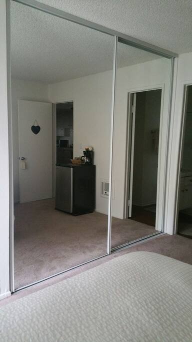 Very large mirrored closet with wooden hangers inside.