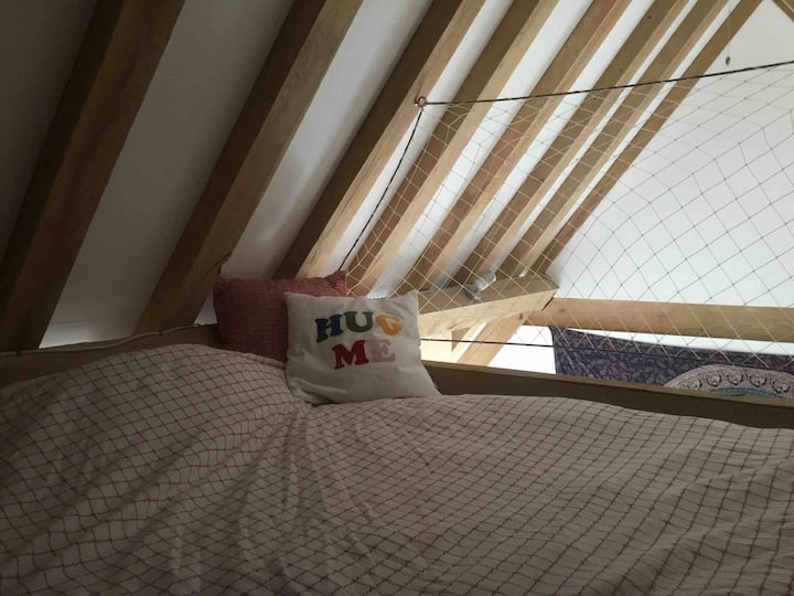 Dubbelmadrass på upphöjd plattform i sovrum två tillgängliga via fast loftstege i trä.