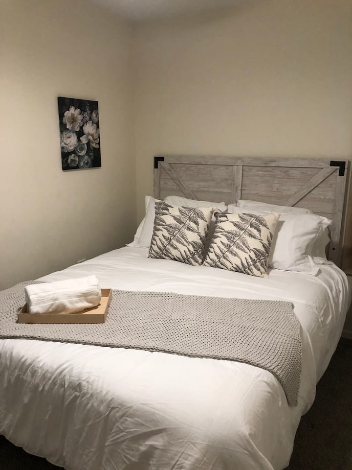 First floor bedroom #1 offers a comfy queen bed, luggage rack, closet space and a beautiful window view of the backyard surrounded by wooded trees and nature. This is a great place to watch the sunrise through the window.
