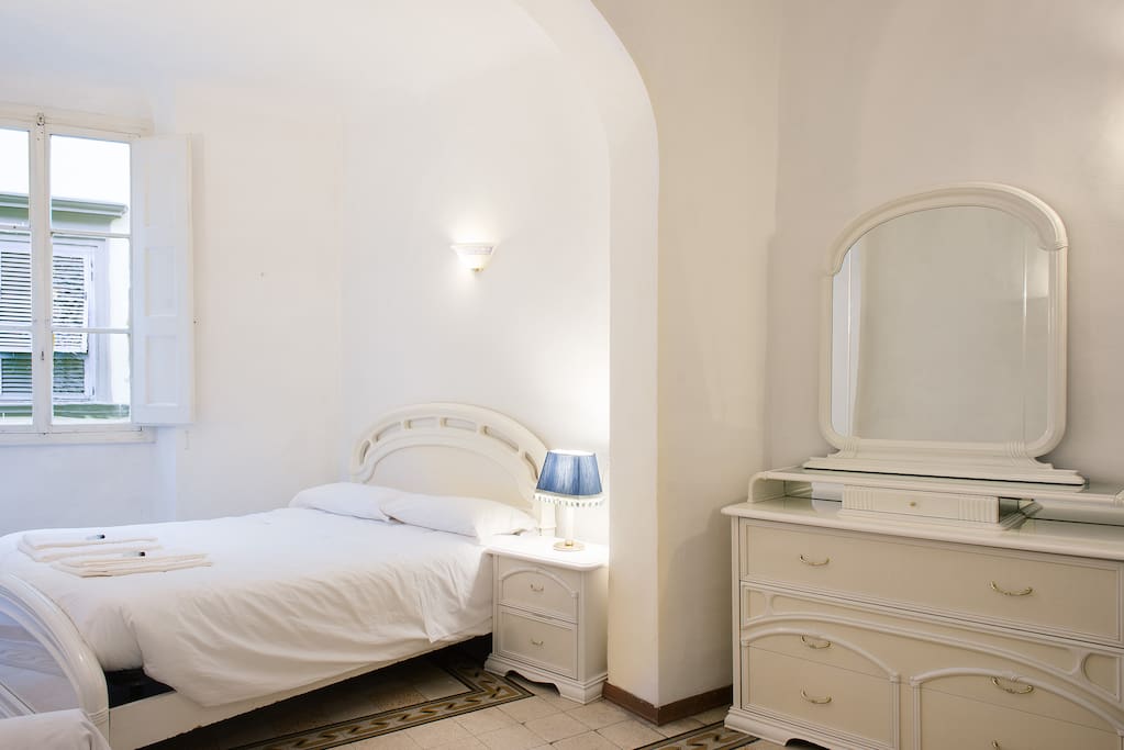Large suite with double bed, dresser, armchair, mirror, sofa, window.