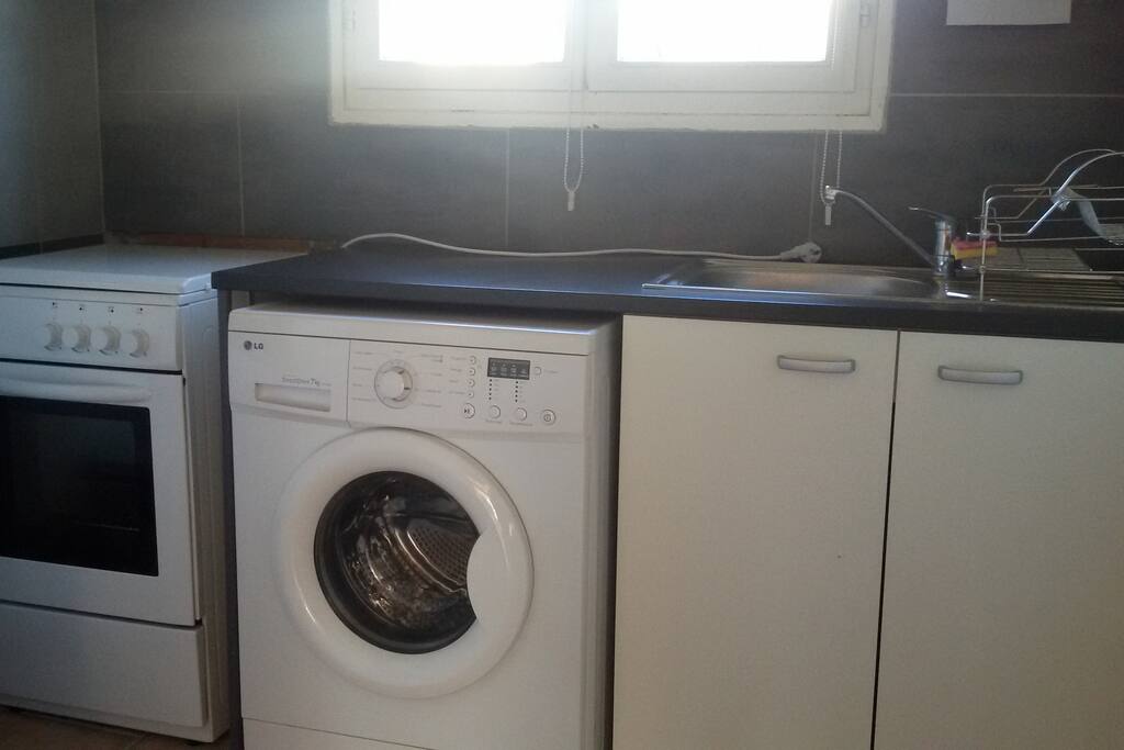 cuisine équipée avec cuisinière à gaz 4 feux, four, micro-ondes, réfrigérateur, lave-linge