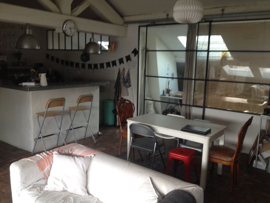 Salon - salle à manger - cuisine avec vue en arrière plan sur la baie vitrée de la chambre