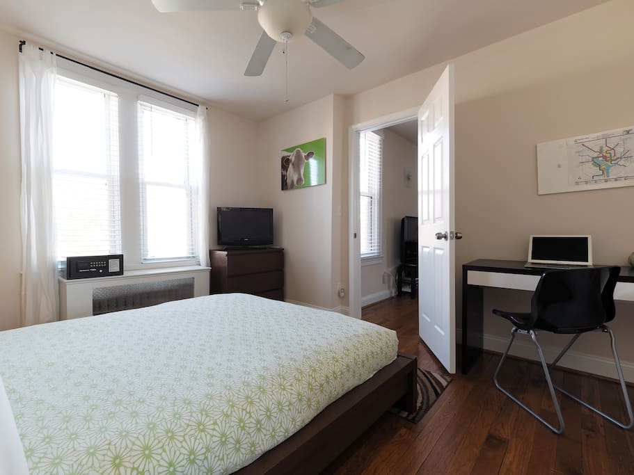 Queen size bed in large bedroom. TV, hotel safe, and workspace.