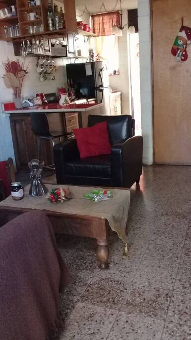 En un ambiente esta la sala y la cocina con una barra para desayunar