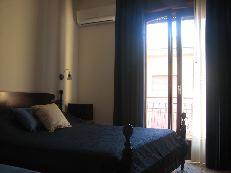 Camera da letto con letto matrimoniale e singolo con accesso al balcone.