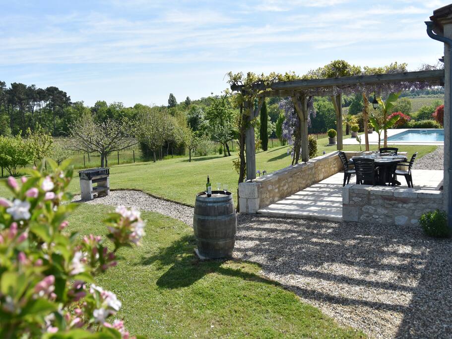 Stone walled patio overlooking garden and pool.