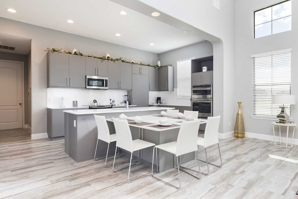 The bright and modern living area features a dining table and a full, grand kitchen.