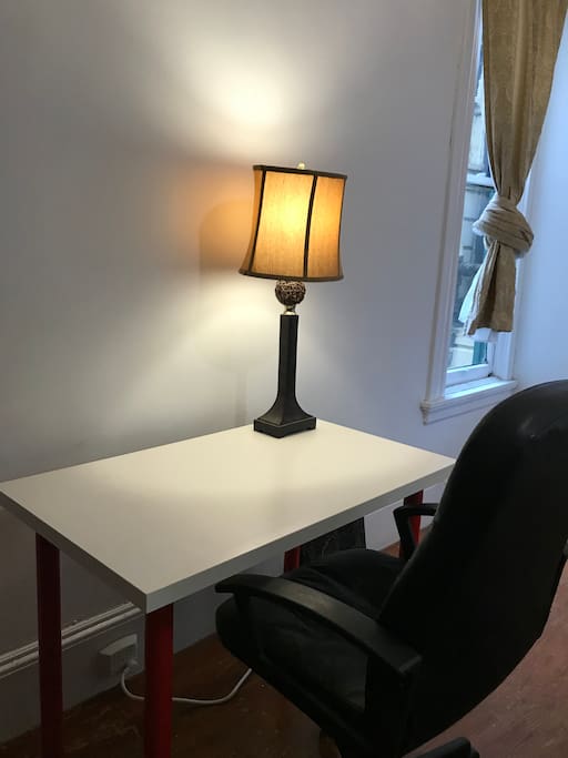 A writing desk, comfortable chair, and table lamp.