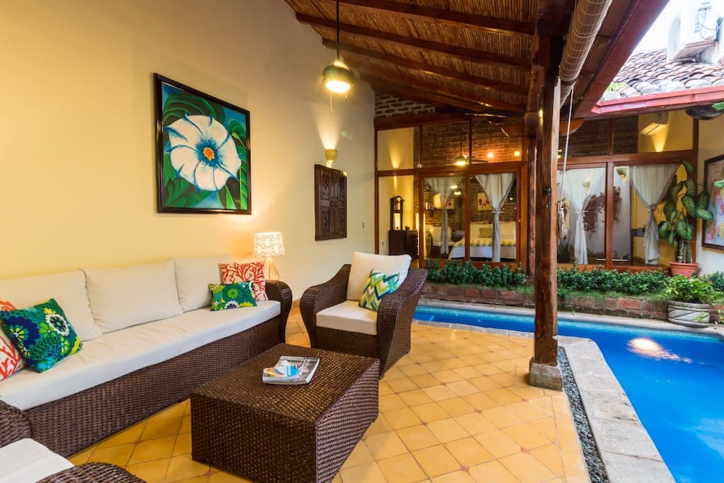 The extra wide sofa and two club chairs were custom made for Casa Romantica in December 2017. Local artisans built the actual furniture by hand, then doubled the cushion height for a more comfortable and relaxing experience (not common in Nicaragua to have deep seating or thicker cushions). Your own private indoor / outdoor pool right in the living room! Large flatscreen TV is directly behind this shot, so it can be seen from sitting area and pool (also has US Netflix, in addition to regular cable)