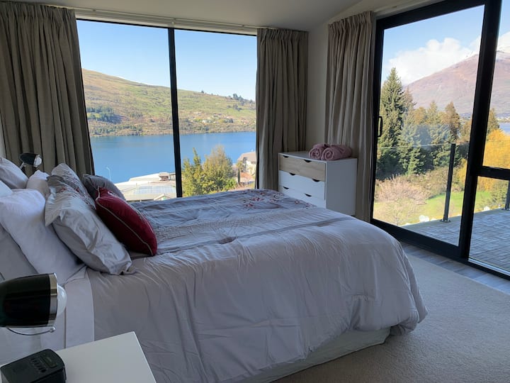 1st bedroom with king  bed and  views of Cecil Peak and Lake Wakatipu. Leads out to balcony. 